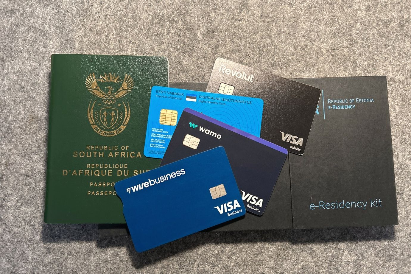 My own South African passport, Estonian e-Residency kit and digital ID card, and the Wise Business, Wamo and Revolut Business cards — my actual Estonian OÜ setup.